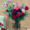 Mixed bouquet of red roses, lilies, and pink carnations in a glass vase