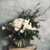 White flowers and greenery arranged in a glass vase