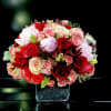 Bouquet of red, pink, and white roses in a square vase