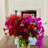 Red and magenta floral arrangement in a clear glass vase