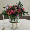 Colorful floral centerpiece in a glass bowl vase on a gold stand