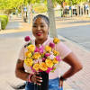 Woman holding a bouquet of yellow and pink flowers in a black vase