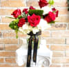 Red roses and white carnations in a glass vase with a black ribbon