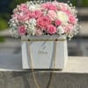 Pink and white roses arranged in a Dior gift box with gold chain handles.