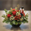 Holiday arrangement with red roses and a nutcracker figurine in a black bowl