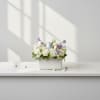 White floral arrangement with pastel Easter eggs in a rectangular vase