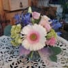 Bouquet of pink and white flowers in a glass vase with a lavender ribbon