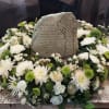 White floral wreath around a memorial stone with a Celtic cross