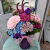 Colorful bouquet in a purple vase with a pink ribbon