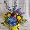 Colorful flower arrangement in a yellow container with blue hydrangea and mixed blooms