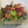 Mixed floral arrangement in a wooden box with orange and red blooms