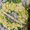 White floral wreath with roses and pale green blooms on a stand
