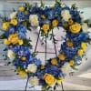 Heart-shaped floral wreath with blue, yellow, and white flowers on an easel