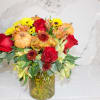 Bouquet of red roses, yellow mums, and pumpkins in a glass vase