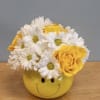 Yellow smiley-face vase holding white daisies and yellow roses
