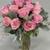 Pink rose bouquet in a clear glass vase with gray-green foliage