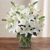White lilies and roses arranged in a clear glass vase