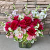 Bouquet of red roses, pink carnations, and white alstroemeria in a glass vase