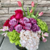 Pink roses, tulips, hydrangeas, and carnations in a low vase