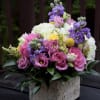 Pink and purple bouquet with white blooms in a square stone vase