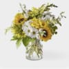 Yellow sunflowers and white daisies in a clear glass vase