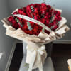 Large bouquet of red roses wrapped in cream paper with a ribbon