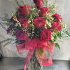 Red roses in a clear glass vase with a pink ribbon