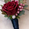 A classic deep red rose boutonniere accented with blush filler flowers and