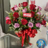 Bouquet of red and lavender roses in a glass vase with a red ribbon