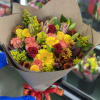 Mixed bouquet of yellow, pink, and red flowers wrapped in brown paper
