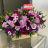 Pink and purple floral arrangement in a wooden box with a butterfly pick