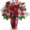 Red roses and pink flowers in a burgundy vase