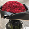 Large bouquet of red roses wrapped in black paper with a satin ribbon