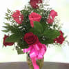 Red roses in a glass vase with a pink ribbon
