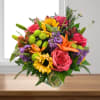 Mixed bouquet of roses, sunflowers, lilies, and purple flowers in a glass vase