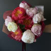 Hand-tied bouquet of pink and white peonies wrapped in paper