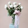 White long-stemmed roses arranged in a clear glass vase create a quietly