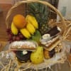 Fruit basket with bananas, pineapple, grapes, pear, mango, and assorted pastries