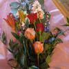 Mixed bouquet with roses, lilies, and blue flowers on pink paper