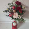 Red roses and white flowers arranged in a Santa-themed vase