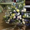 Large bouquet of white, yellow, and blue flowers wrapped in clear plastic