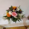 Mixed bouquet of pink and orange roses with white filler flowers in a glass vase