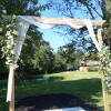 White floral arch draped with sheer fabric outdoors