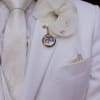 White orchid boutonniere on a white suit jacket with a photo charm