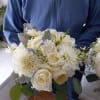 Person holding a white bouquet with roses and dahlias