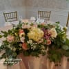 Large floral centerpiece with pink and cream flowers on a round table