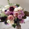Handheld bouquet of roses in blush, lavender, white, and burgundy