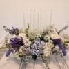 Low floral centerpiece with white and purple flowers on a table