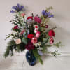 Mixed holiday bouquet in a blue glass vase with red, pink, and white flowers