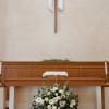 White floral arrangement beneath a church altar with a cross above